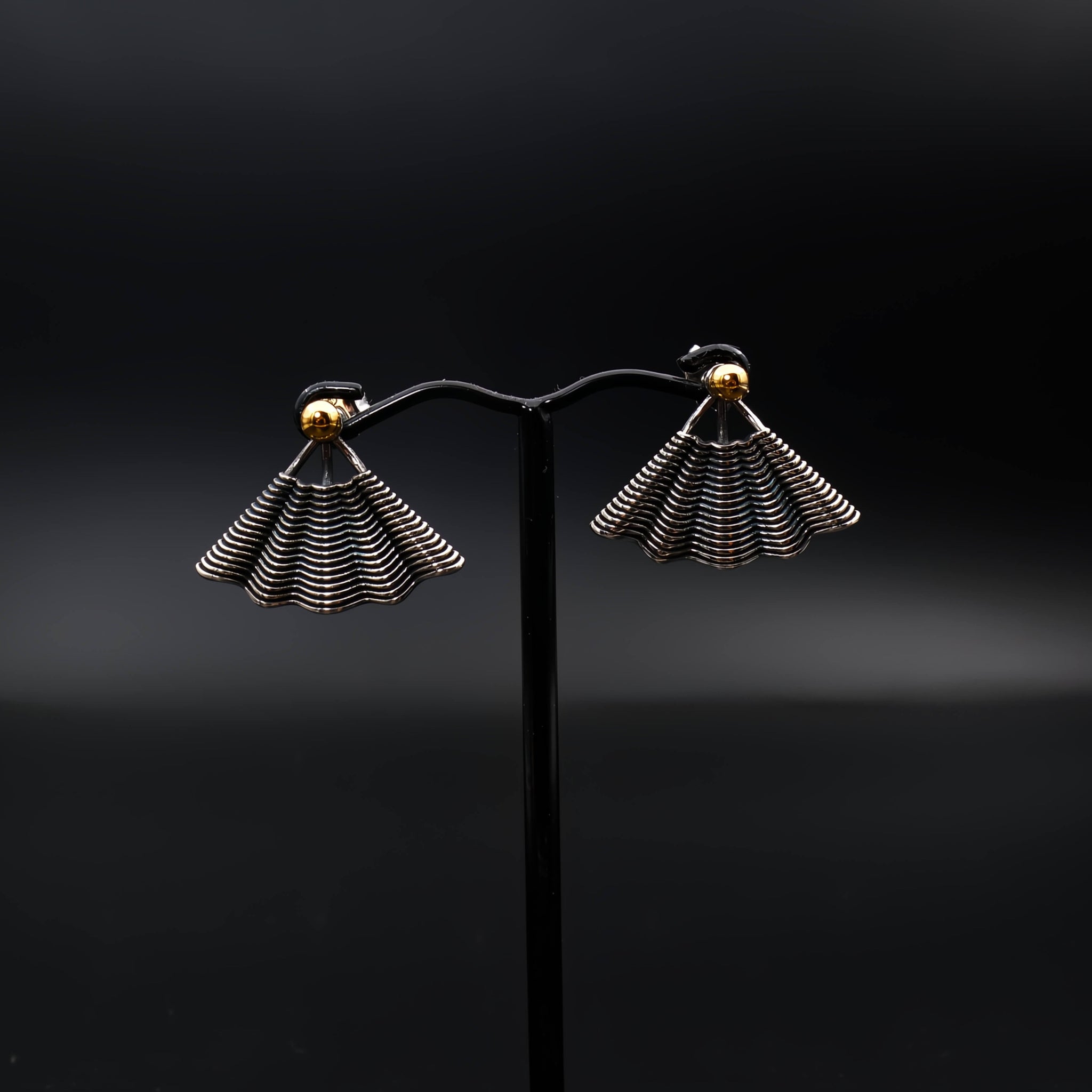 This file contains a concise description of handcrafted earrings made from sterling silver and 14K gold. The earrings have a unique hand fan shape inspired by straw basket textures, with a small gold granule at the top. They are described as elegant, versatile, and suitable for any occasion.