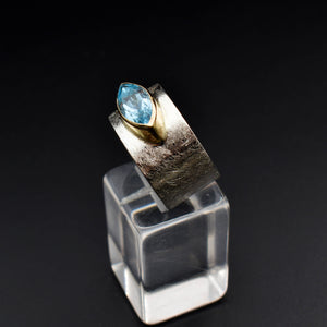 This document provides a crafted description for a handmade ring named 'Azure Elegance.' The ring features a subtly wide silver band with a matte finish and showcases a marquise-cut aquamarine at the top, embraced by a 14-karat yellow gold bezel. The description highlights the handcrafted nature, unique design, and key materials used, emphasizing its timeless beauty and modern allure. Additionally, the document includes suggested names and tags for the ring to enhance its discoverability on an eshop page.