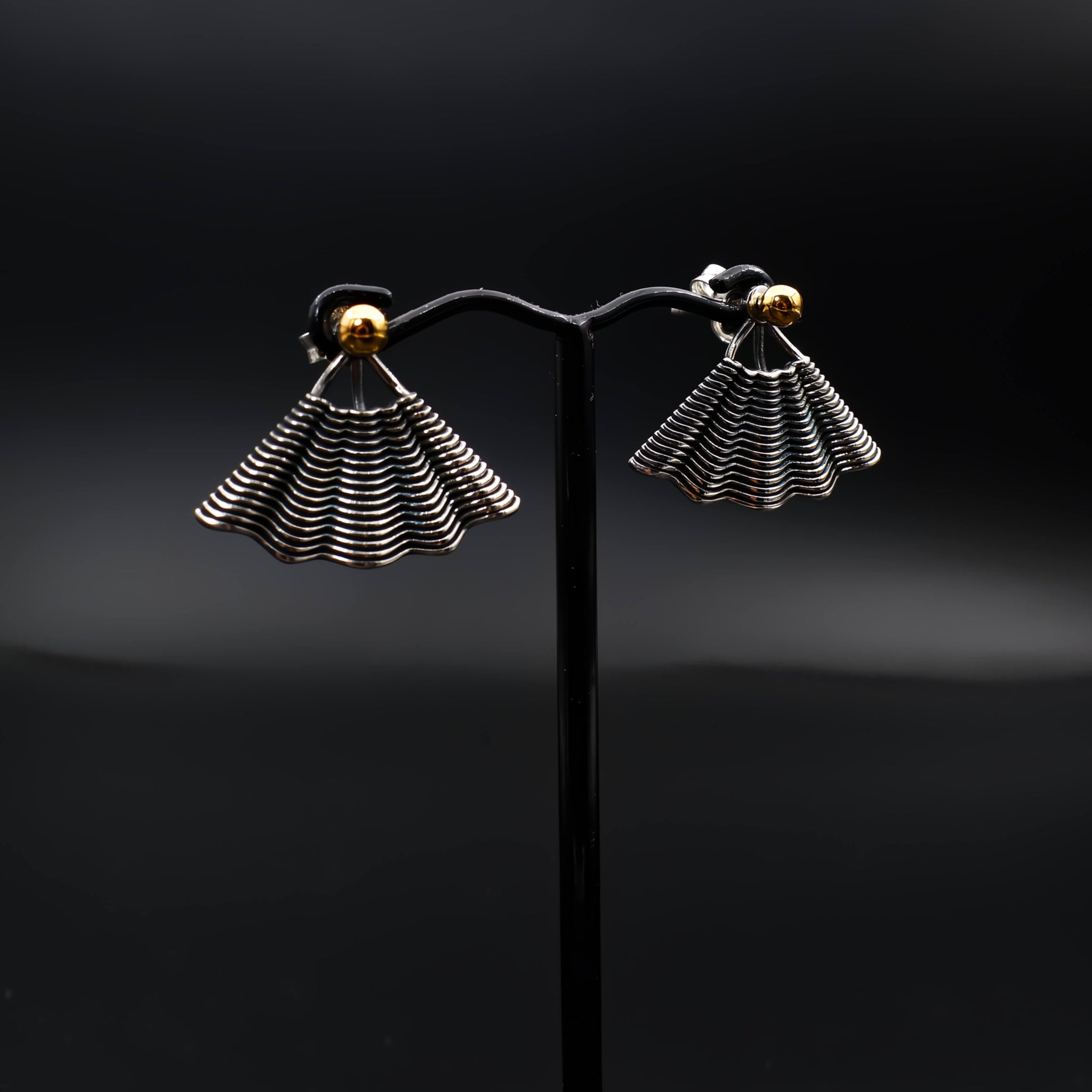 This file contains a concise description of handcrafted earrings made from sterling silver and 14K gold. The earrings have a unique hand fan shape inspired by straw basket textures, with a small gold granule at the top. They are described as elegant, versatile, and suitable for any occasion.