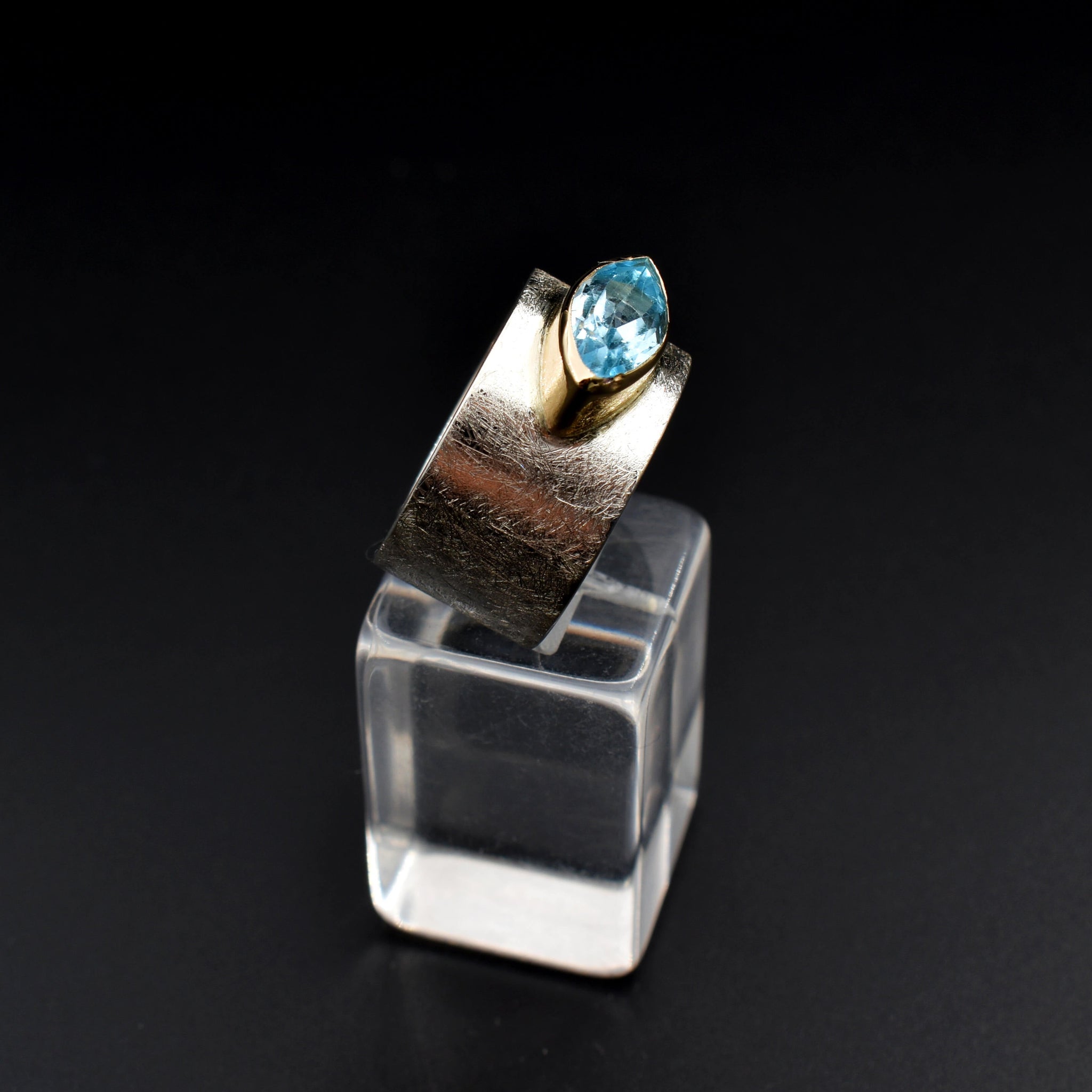 This document provides a crafted description for a handmade ring named 'Azure Elegance.' The ring features a subtly wide silver band with a matte finish and showcases a marquise-cut aquamarine at the top, embraced by a 14-karat yellow gold bezel. The description highlights the handcrafted nature, unique design, and key materials used, emphasizing its timeless beauty and modern allure. Additionally, the document includes suggested names and tags for the ring to enhance its discoverability on an eshop page.