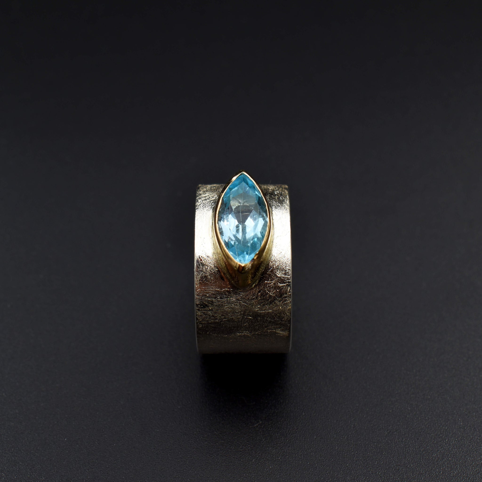 This document provides a crafted description for a handmade ring named 'Azure Elegance.' The ring features a subtly wide silver band with a matte finish and showcases a marquise-cut aquamarine at the top, embraced by a 14-karat yellow gold bezel. The description highlights the handcrafted nature, unique design, and key materials used, emphasizing its timeless beauty and modern allure. Additionally, the document includes suggested names and tags for the ring to enhance its discoverability on an eshop page.