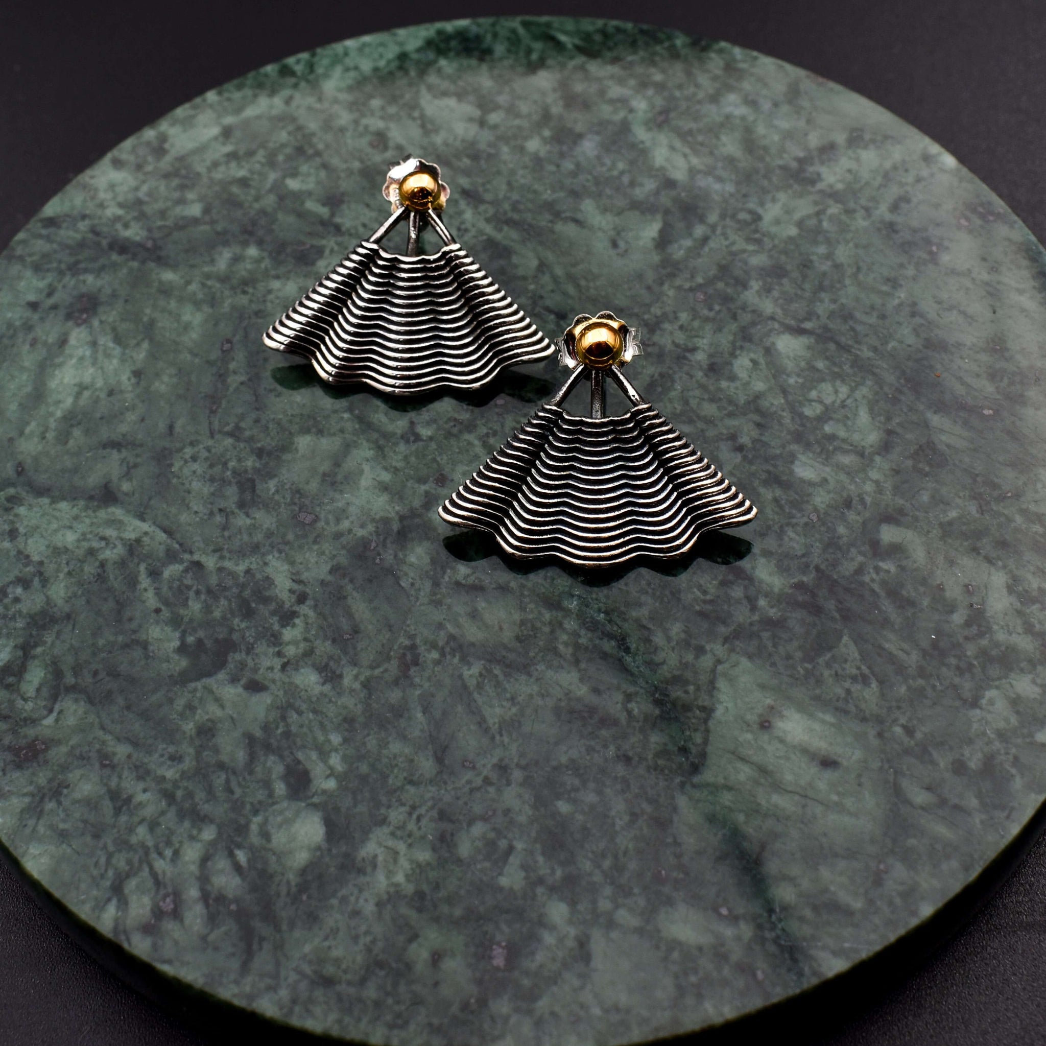 This file contains a concise description of handcrafted earrings made from sterling silver and 14K gold. The earrings have a unique hand fan shape inspired by straw basket textures, with a small gold granule at the top. They are described as elegant, versatile, and suitable for any occasion.