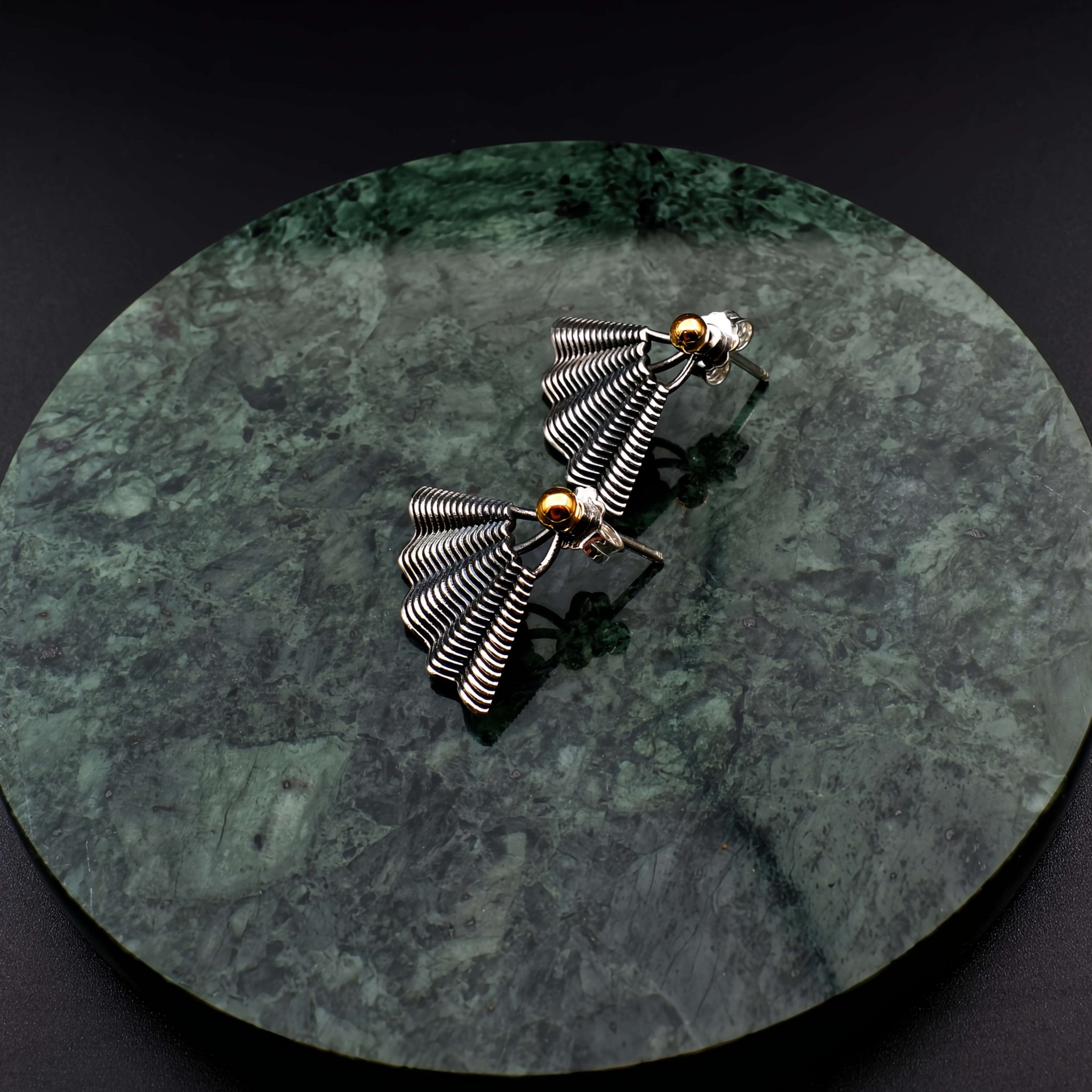 This file contains a concise description of handcrafted earrings made from sterling silver and 14K gold. The earrings have a unique hand fan shape inspired by straw basket textures, with a small gold granule at the top. They are described as elegant, versatile, and suitable for any occasion.