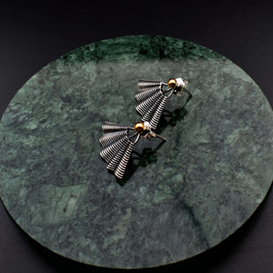 This file contains a concise description of handcrafted earrings made from sterling silver and 14K gold. The earrings have a unique hand fan shape inspired by straw basket textures, with a small gold granule at the top. They are described as elegant, versatile, and suitable for any occasion.