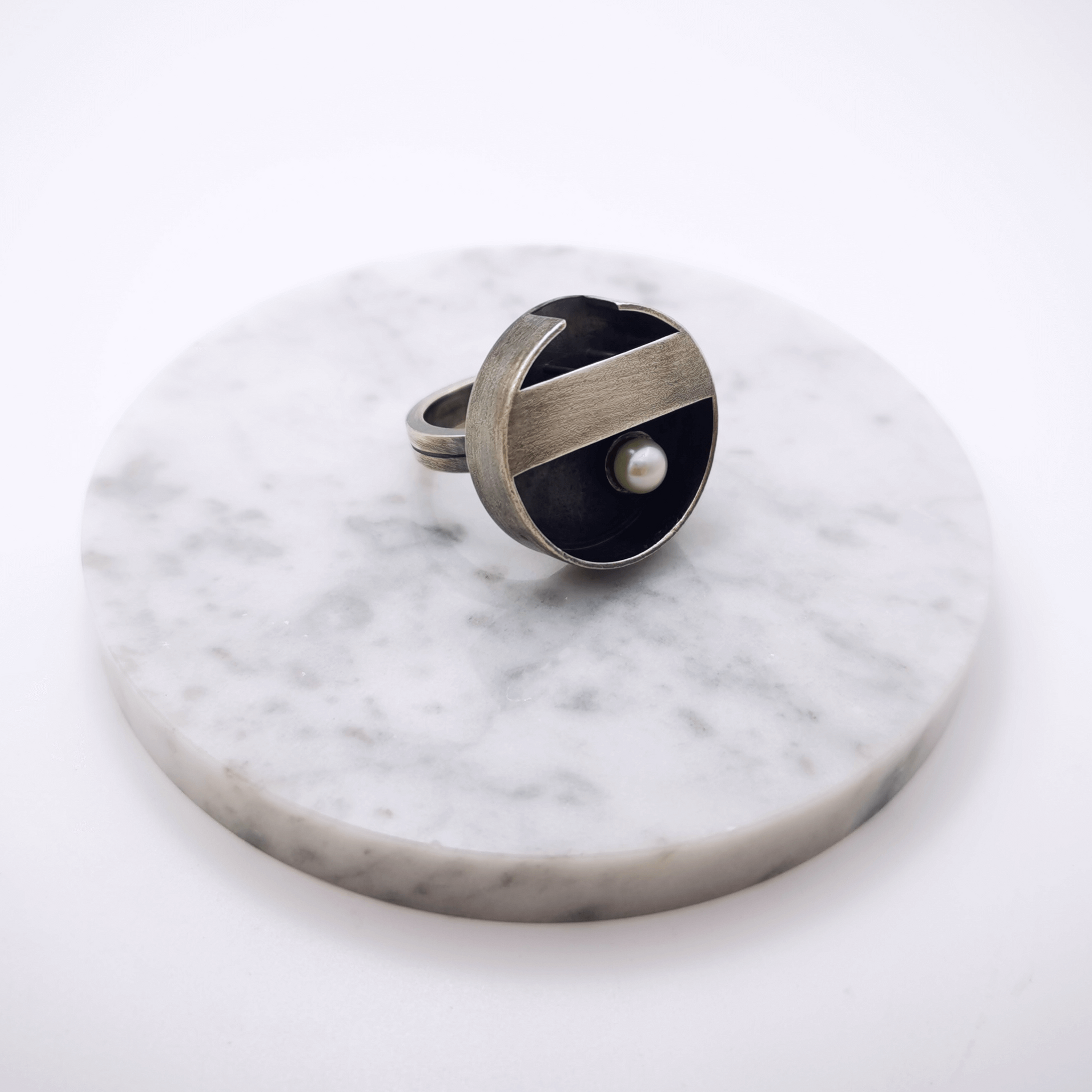 Minimal handcrafted silver ring with a natural white pearl at the centre of the ring, inspiration came from a zen garden in Japan. The ring is oxidized.