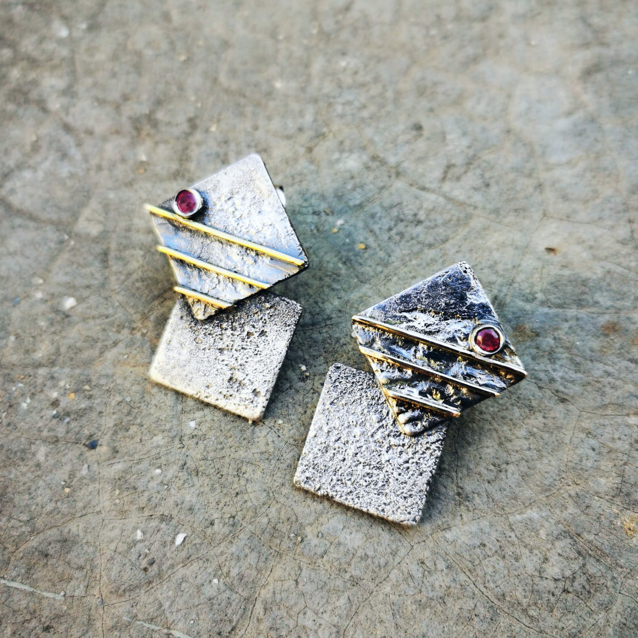 Unique handcrafted silver earrings with gold stripes 14 Karat and a pair of natural round ruby. The earrings are oxidized except the gold parts.